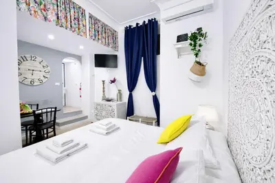 a white bedroom with a white bed with pink and yellow pillows at Navona cozy Loft in Rome