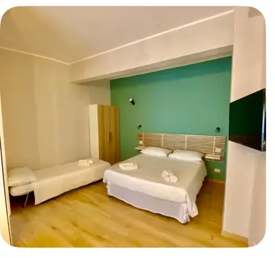 a bedroom with two beds and a green wall at Monolocale Urban House Marconi in Rome