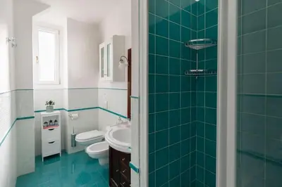 a green tiled bathroom with a toilet and a sink at G & G Maisonette Testaccio in Rome