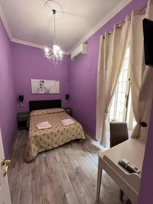 a purple bedroom with a bed and a table at Guest House Biondi Cavour in Rome