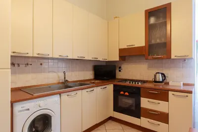 a kitchen with white cabinets and a washing machine at GuestHost - The secret garden of Rome! Apt x2 in Rome