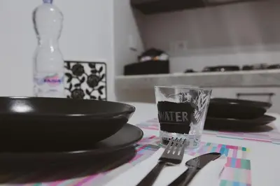 a glass of water sitting on top of a table with plates and bowls at A casa di Elly 2 in Rome