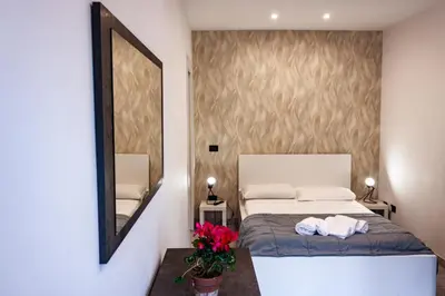 a bedroom with a bed and a mirror and flowers at Domus Marconi Roma in Rome