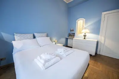 a blue bedroom with a white bed with towels on it at Trastevere 2 BR Cozy Apartment in Rome