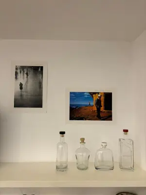 three glass bottles sitting on a shelf with pictures at BBB House in Rome