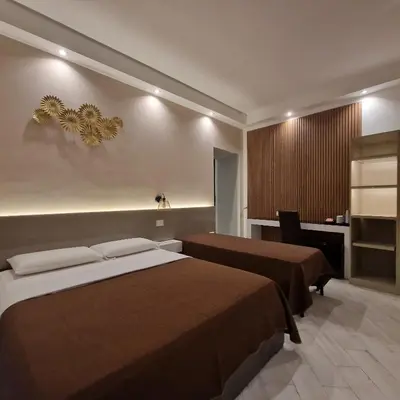 a hotel room with two beds and a desk at B&B Sol Romae in Rome