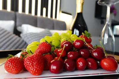 a plate of strawberries and grapes and a bottle of wine at HeySuite - Luxury House - ROMA Trastevere in Rome
