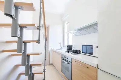 a kitchen with white counters and a spiral staircase at Balestrari Boutique Apartment in Rome
