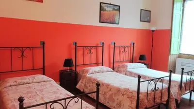 three beds in a room with red walls at Rome Near Colosseum in Rome