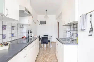 a white kitchen with a sink and a table at Ambra's bright apartment in Rome