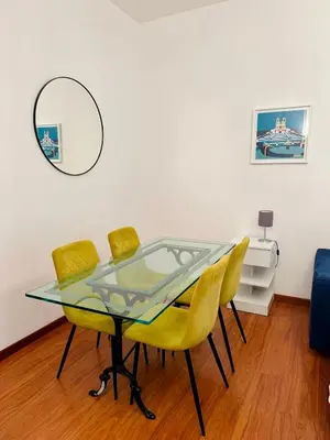 a dining room with a glass table and yellow chairs at Comodo appartamento a pochi passi dalla fermata Porta Metronia Metro C in Rome