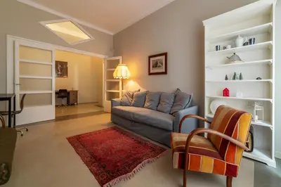 a living room with a blue couch and a red rug at GuestHost - Piazza Bainsizza Elegant Apartment in Rome