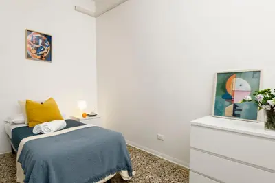 a bedroom with a bed with a blue blanket and yellow pillow at San Giovanni Home in Rome