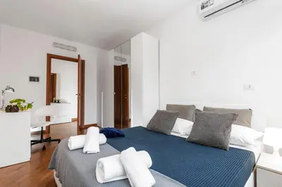 a white bedroom with a blue bed with white pillows at SkyView Home in Rome