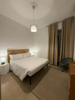 a white bedroom with a bed and a chair at Pietra Apartment,Colosseo in Rome