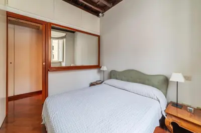a bedroom with a white bed and a mirror at GuestHost - Campo de Fiori Unique Apartment in Rome