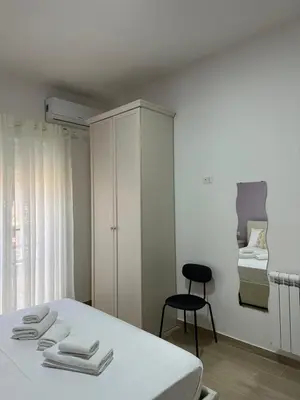 a white bedroom with a bed and a chair at The Roman Guesthouse in Rome