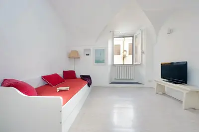 a white living room with a red couch and a television at Cimarra Apartment in Rome