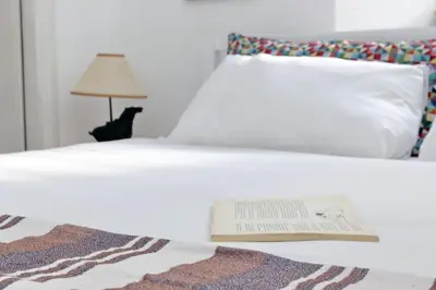 a book laying on a bed with a lamp at Cimarra Apartment in Rome