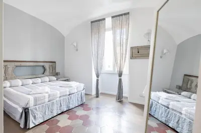 a white bedroom with two beds and a mirror at Casa Esquilina in Rome
