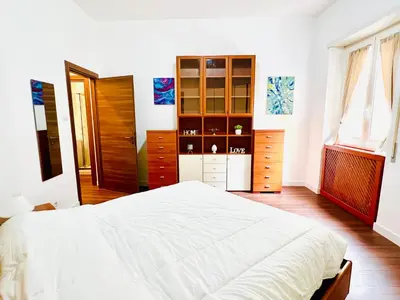 a bedroom with a white bed and a dresser at Elegant Apartment Villa Bianca in Rome