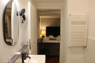 a bathroom with a sink and a mirror and a bedroom at AD HOMES - Saint Peter Loft in Rome