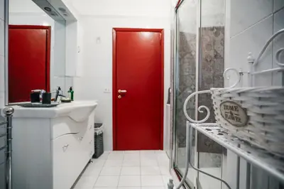 a red door in a bathroom with a sink at San Pietro Intero Alloggio -PANE&MELE- in Rome