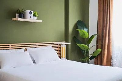 a bedroom with a white bed and a green wall at Basilica San Paolo - Home Cinema e Vasca Idromassaggio in Rome