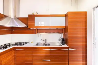 a kitchen with wooden cabinets and a sink at La corte di Merlino - Apt centrale di pregio in Rome