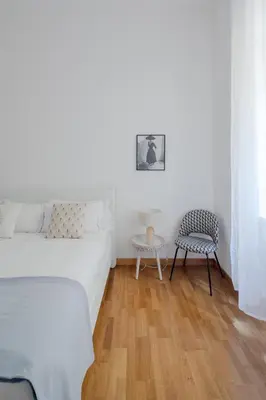 a white bedroom with a bed and a chair at Elegant apartment with patio at Piazza Navona in Rome
