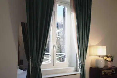 a window with green curtains in a room at Urbana Suite in Rome