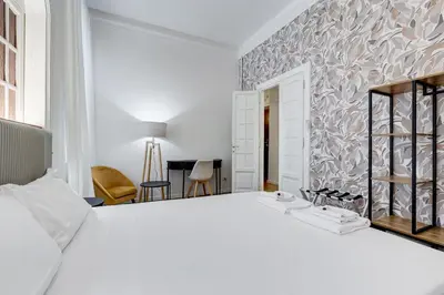 a bedroom with a large white bed with a wall at BMGA l Gracchi Lux Lovely 3Bdr Apartment in Rome