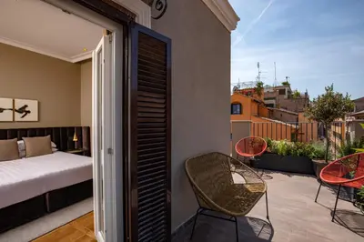 a bedroom with a bed and chairs on a balcony at Condotti Belvedere in Rome