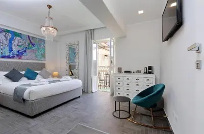 a white bedroom with a bed and a chair at Boutique Suites della Croce in Rome