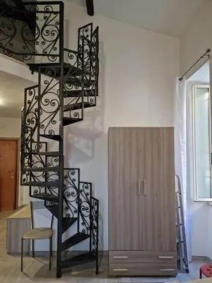 a spiral staircase in a living room with a chair at Loftiense Roma in Rome