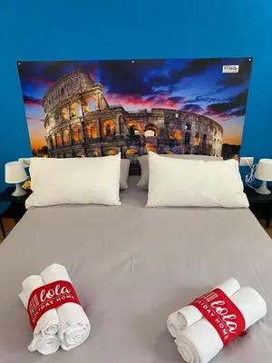 a large bed with two cocacola slippers on it at Lola Holiday Home, Roma Ostiense in Rome