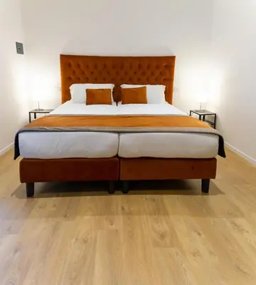 a bedroom with a large bed with a wooden headboard at Michelangelo Vatican Guest House in Rome