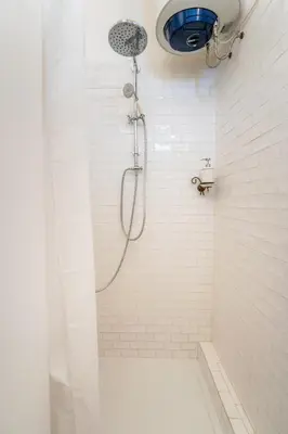 a shower in a white tiled bathroom at Casetta Giolitti, Cozy Apt in the Heart of Rome in Rome