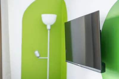 a flat screen tv attached to a green wall at BigFamilyRome-Vatican&Aurelio in Rome