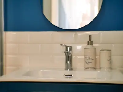 a bathroom sink with a mirror and a soap dispenser at Chic Modern 2-Bedroom near Metro in Rome