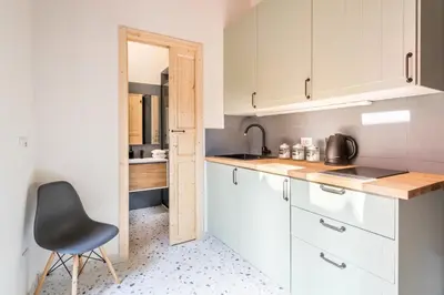 a kitchen with white cabinets and a black chair at FAMM Apartments - Open space in Trastevere in Rome