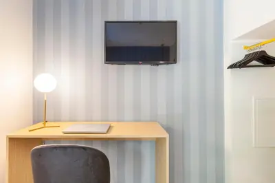 a desk with a laptop and a television on a wall at Mom's home - A few stops from the city centre in Rome