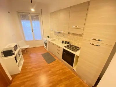 a kitchen with wooden floors and white appliances at Golden Essence Apartment - terrace & metro in Rome