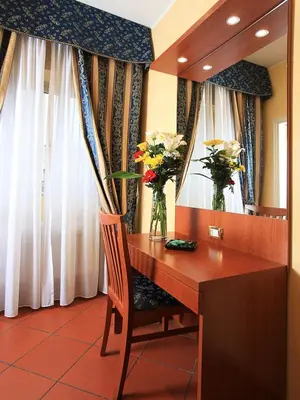 a desk with flowers in a room with curtains at Casa Di Santa Francesca Romana a Ponte Rotto in Rome