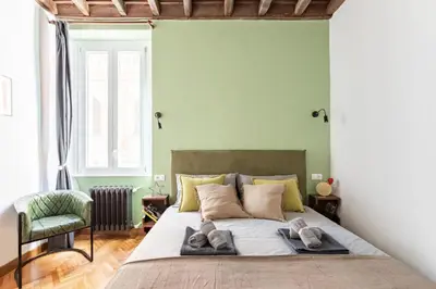 a bedroom with a large bed and a chair at Trastevere 68 Stylish Apartment in Rome