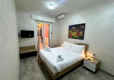 a bedroom with a white bed and a television at La Palmetta - Vicino Metro A in Rome
