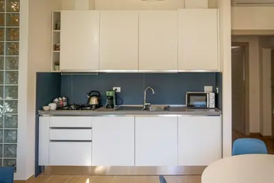 a kitchen with white cabinets and a sink at Little Blue Apartment in Rome
