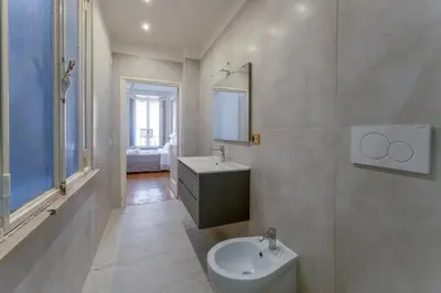 a white bathroom with a sink and a mirror at Palazzo Pamphili Apartment in Rome