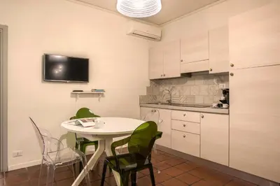 a kitchen with a table and green chairs in a room at Nettuno Apartment in Rome