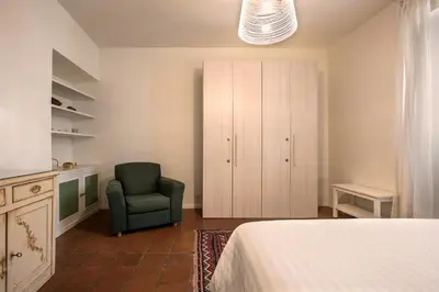 a bedroom with a bed and a chair and a cabinet at Nettuno Apartment in Rome